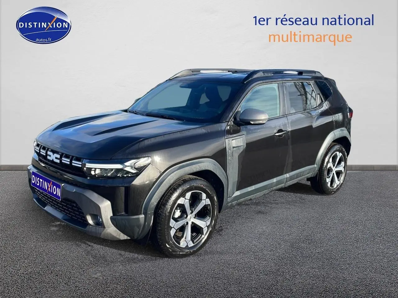 SUV Dacia Duster noir en 3/4 avant droit, avec jantes alu et barres de toit visibles.