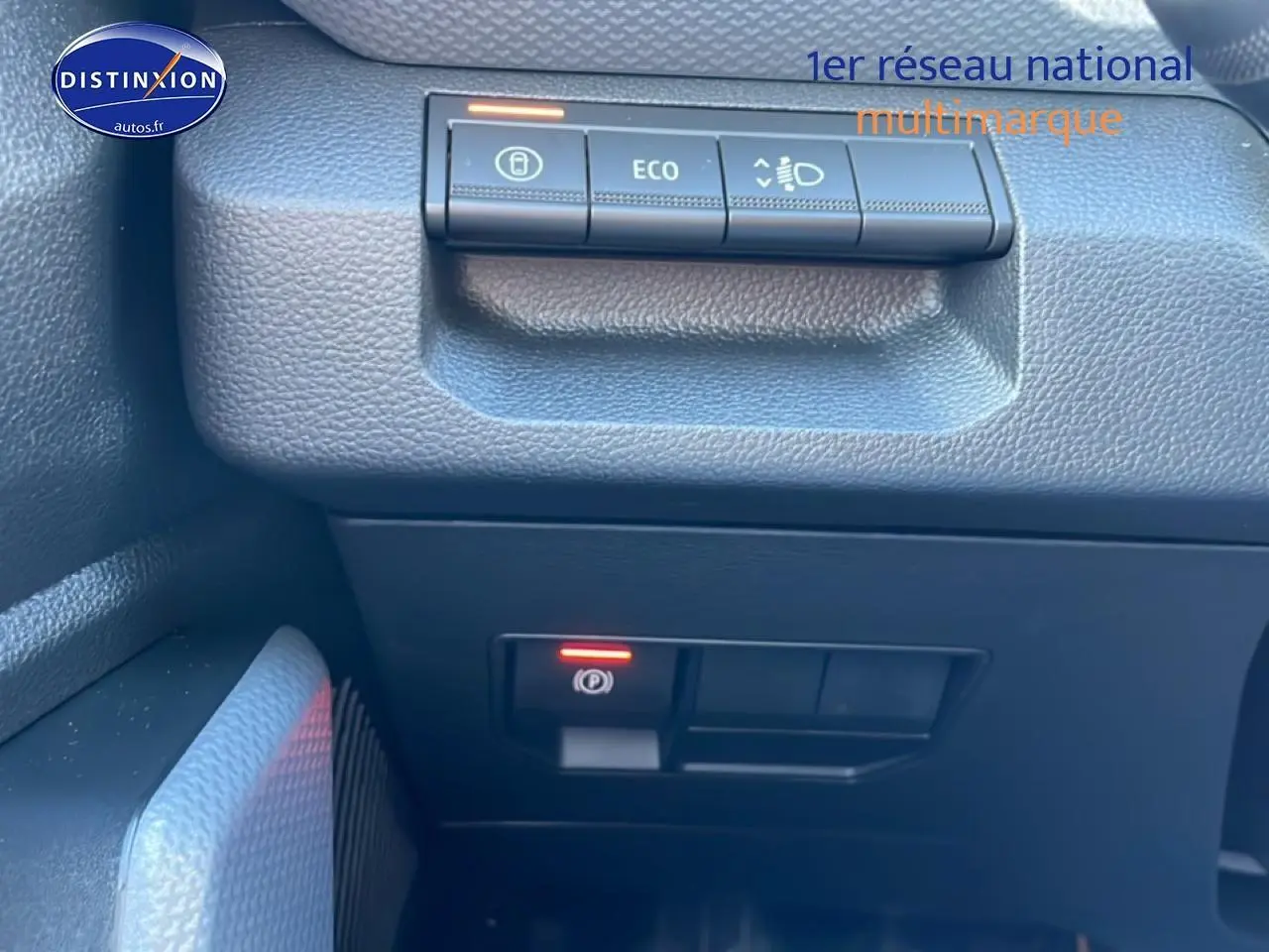 Gros plan sur les commandes de tableau de bord noir du Dacia Duster 1.2 mild hybrid 140 Journey, avec bouton ECO et frein à main électronique.