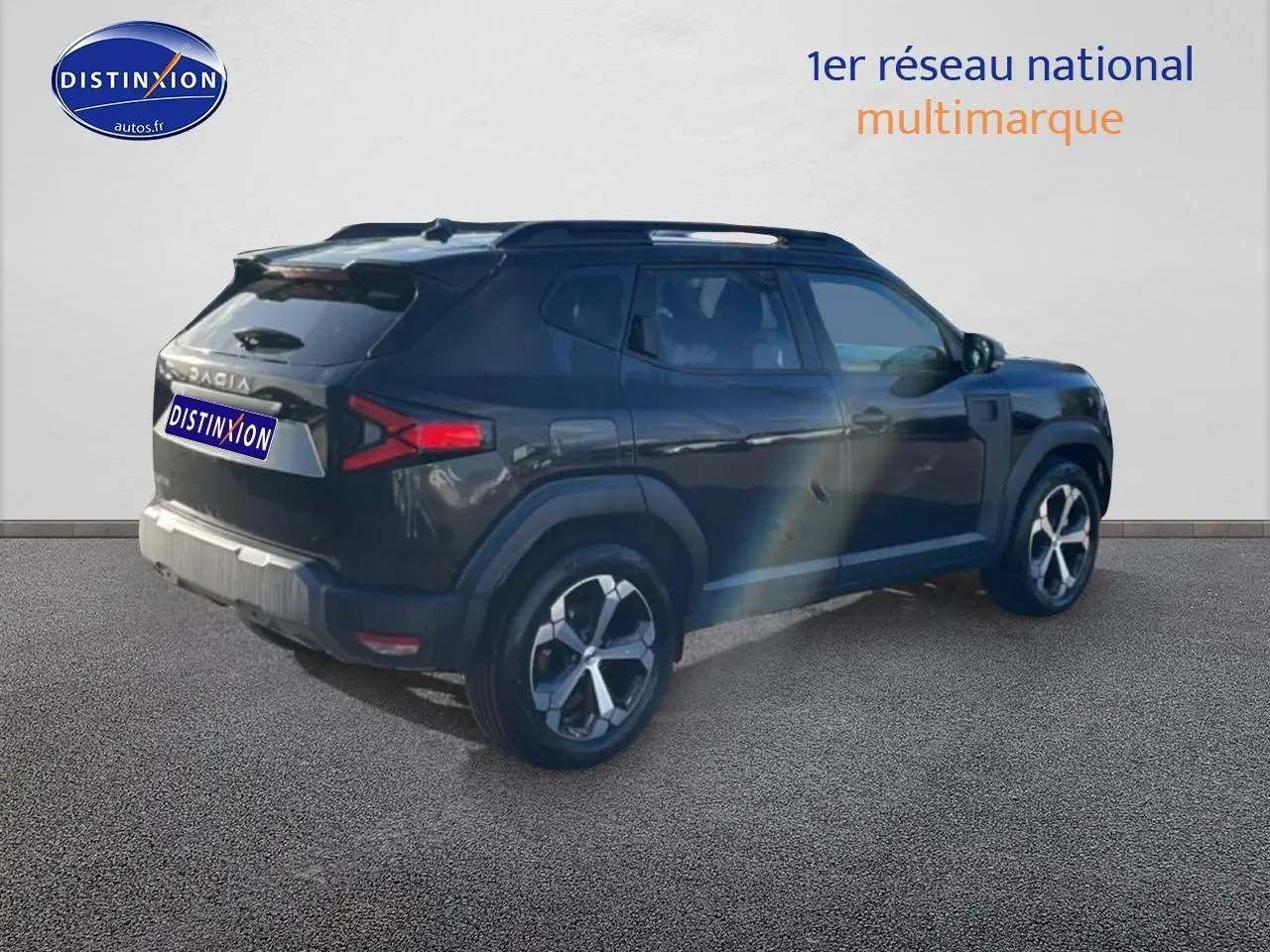 Vue 3/4 arrière droite du Dacia Duster noir 2026 avec jantes alliage et barres de toit visibles.