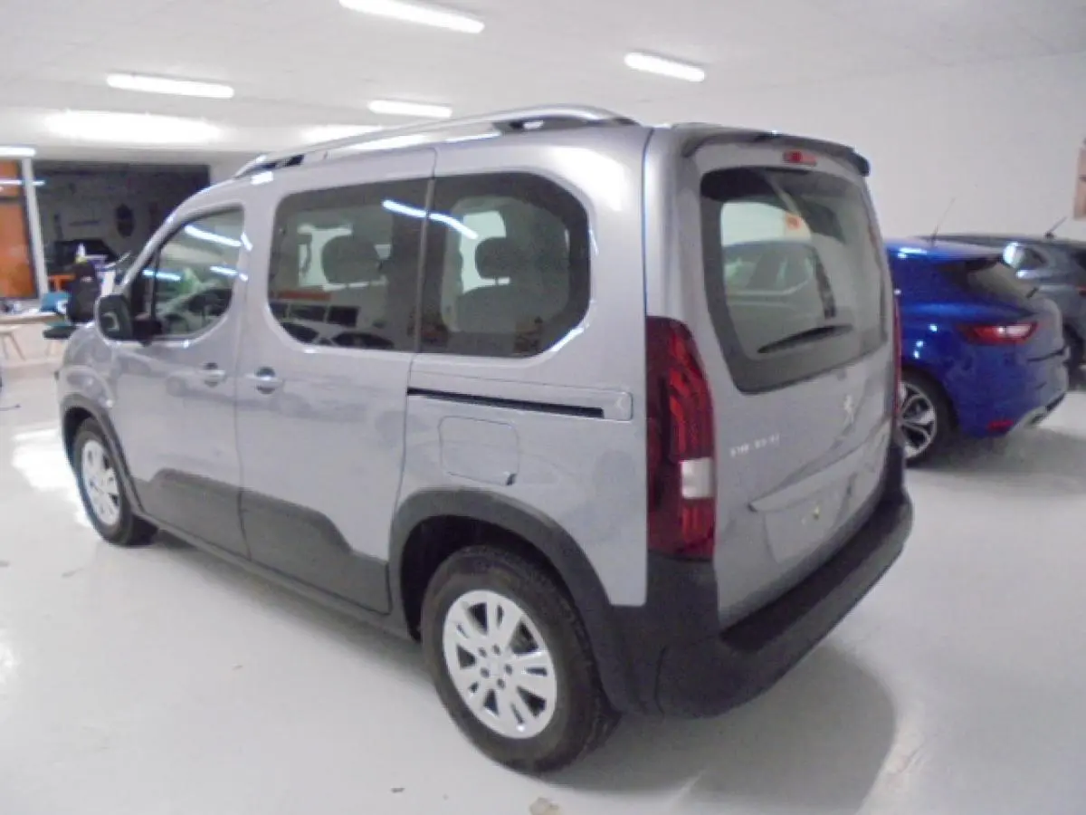 Peugeot Rifter gris Artense vu en 3/4 arrière droit, avec portes coulissantes et protections noires sur les bas de caisse.