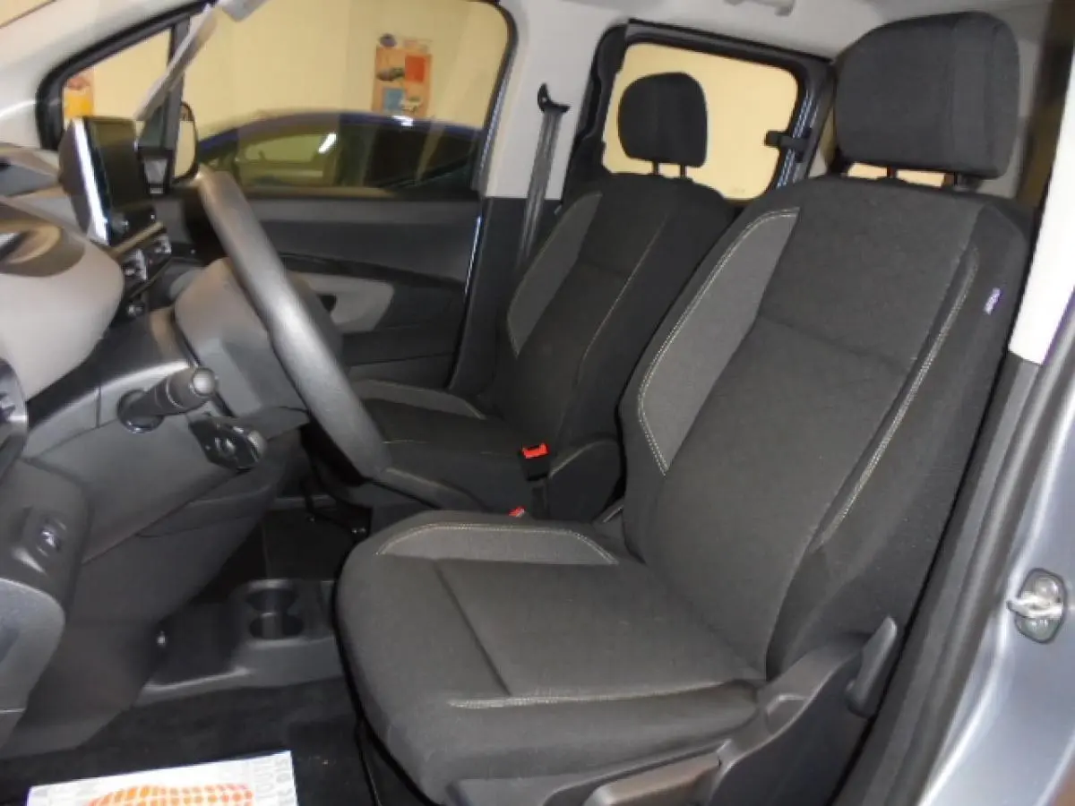 Vue intérieure côté gauche du Peugeot Rifter 2020 gris Artense, montrant les sièges avant en tissu noir avec surpiqûres grises.