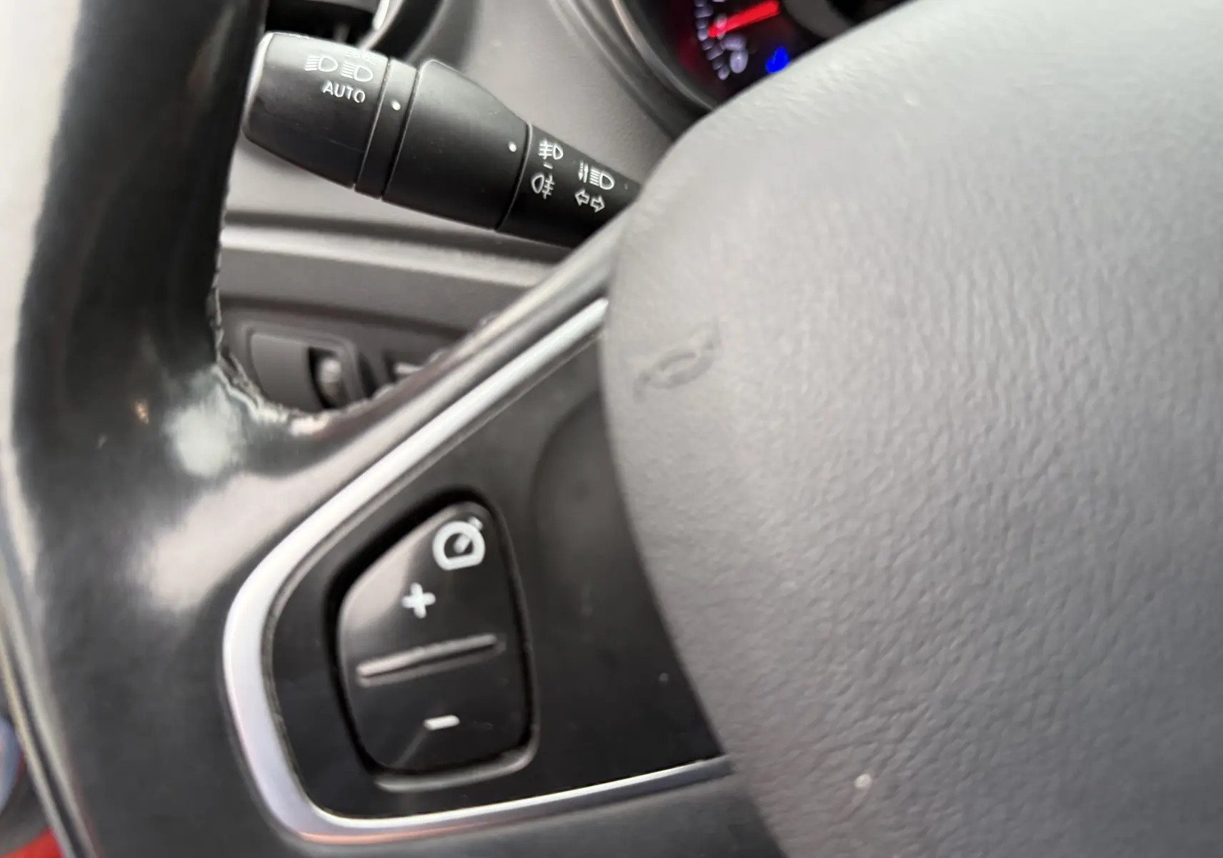 Gros plan sur le volant noir du Renault Captur rouge 2017, avec commandes intégrées visibles côté gauche.