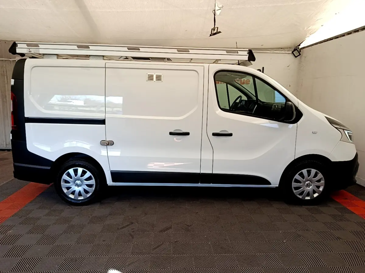 Vue de profil côté droit du fourgon blanc Renault Trafic L1H1 avec galerie de toit et jantes acier.