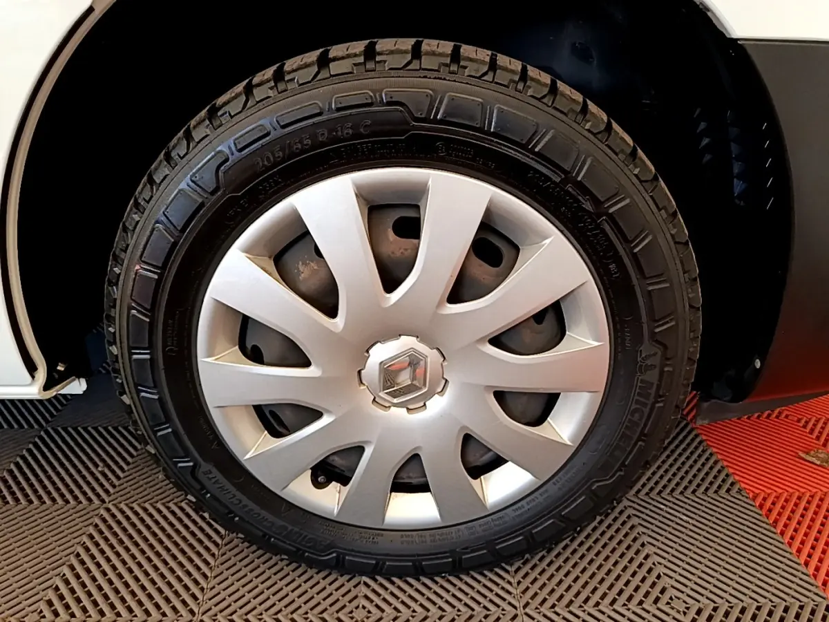 Gros plan sur la roue avant droite d’un Renault Trafic blanc, avec jante en alliage et logo Renault au centre.