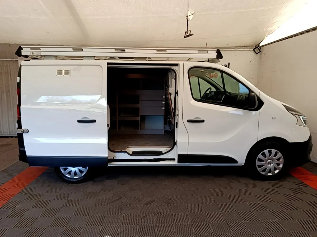 Vue latérale droite d’un Renault Trafic Fourgon blanc 2021 avec porte coulissante ouverte et galerie sur le toit.