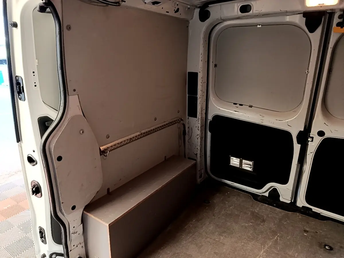 Intérieur du fourgon Renault Trafic L1H1 blanc, vue de l'espace de chargement avec parois et porte arrière ouvertes.