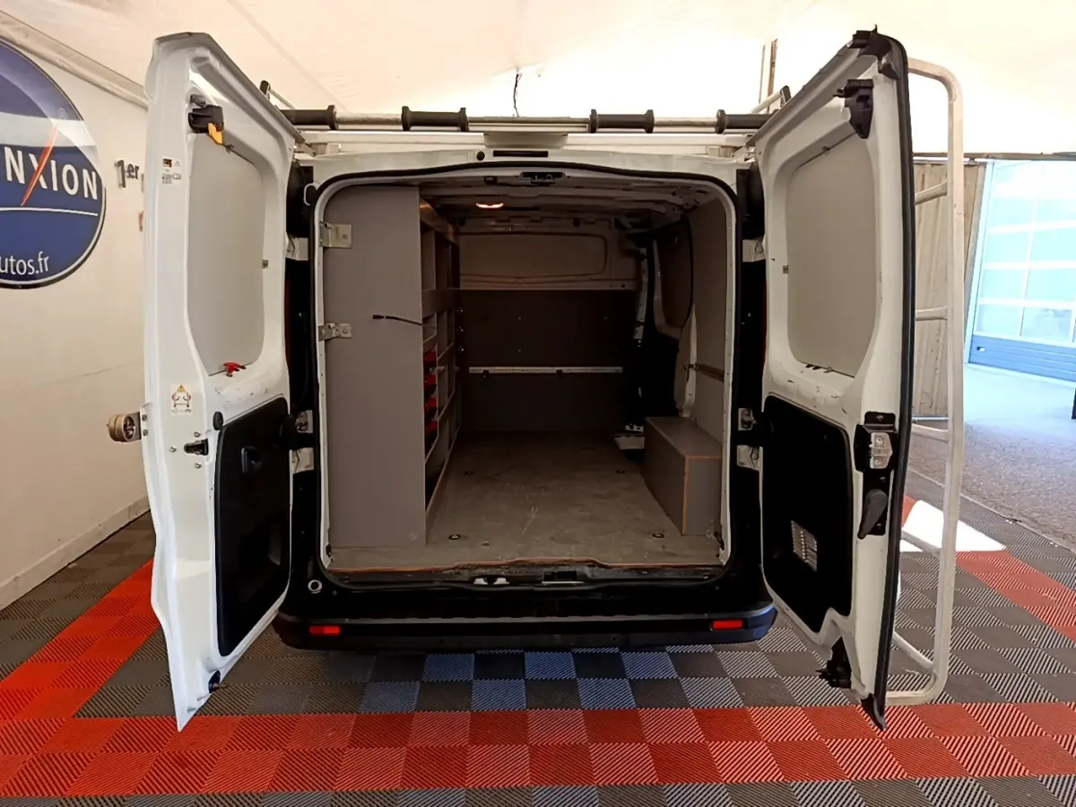 Vue arrière du Renault Trafic Fourgon blanc avec portes ouvertes montrant l'espace de chargement aménagé.