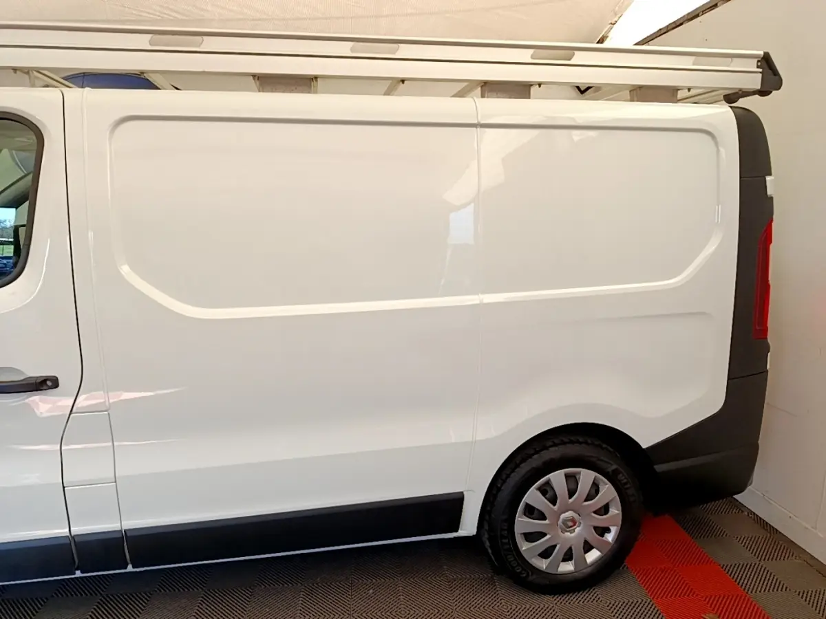Vue latérale droite d’un Renault Trafic Fourgon blanc L1H1 2021 avec jante argentée et galerie de toit.