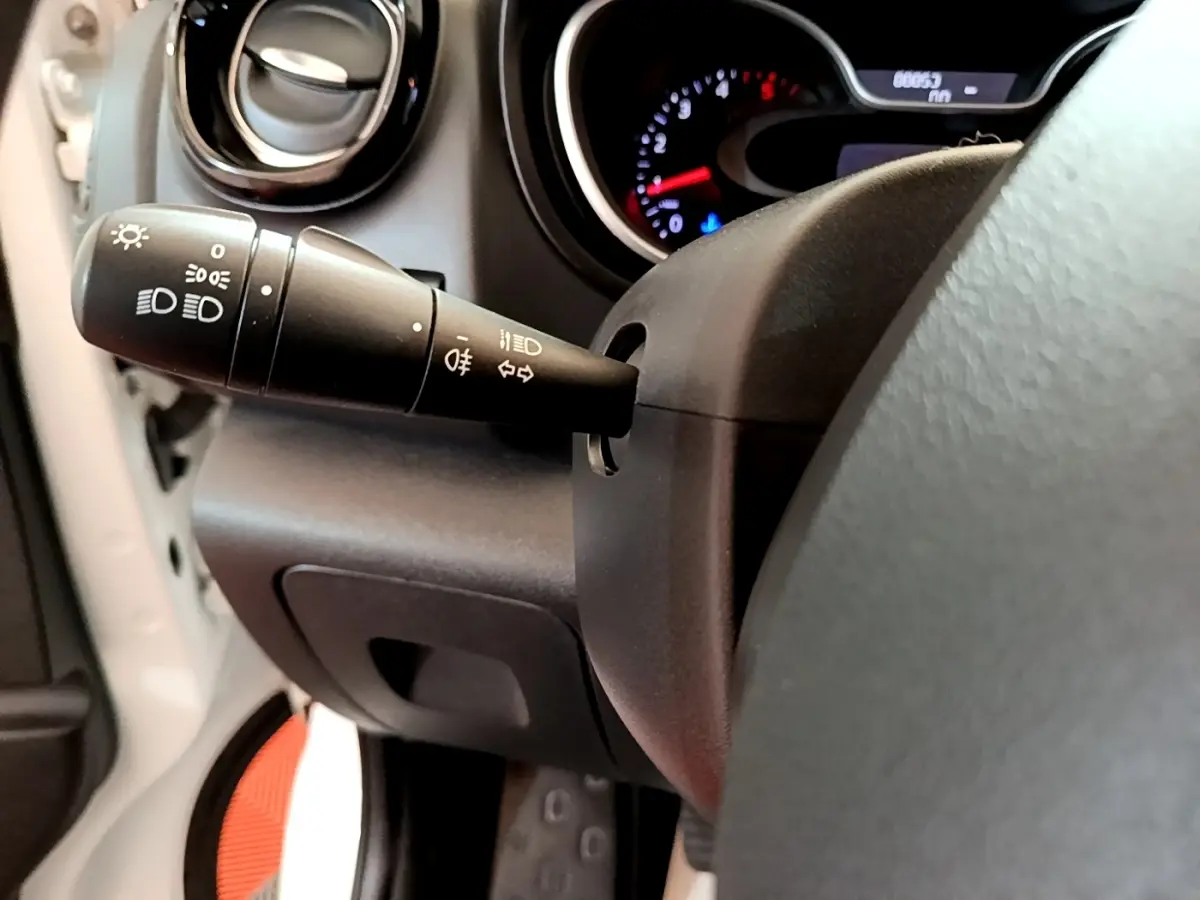 Gros plan sur la commande des feux et clignotants à gauche du volant dans l'habitacle du Renault Trafic blanc.