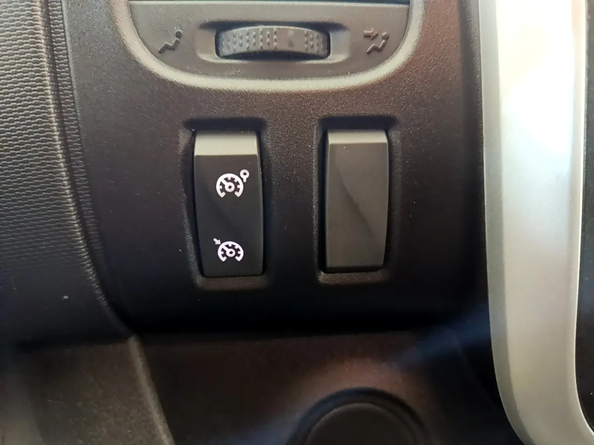 Gros plan sur les boutons de commande du régulateur de vitesse dans l’habitacle du Renault Trafic Fourgon blanc 2021.