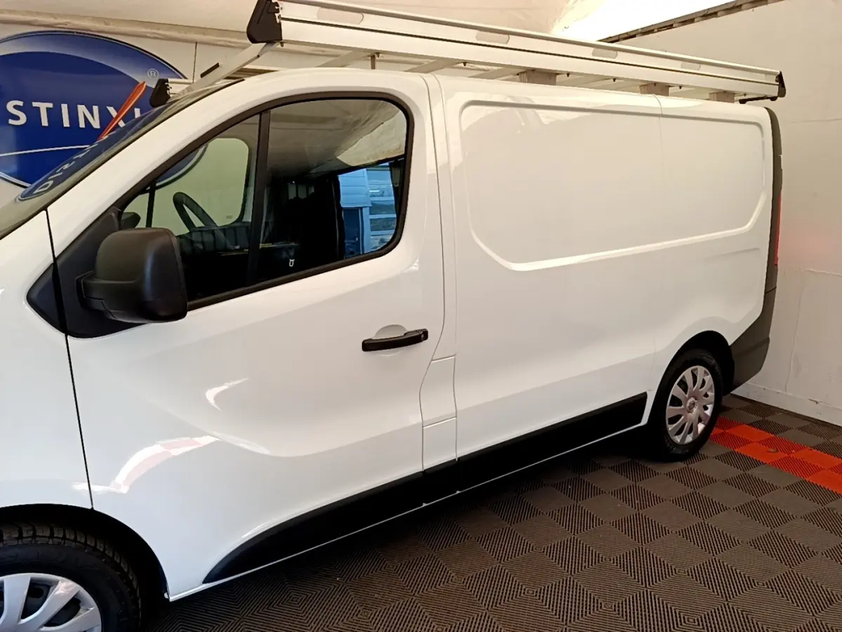 Vue de profil côté gauche du fourgon blanc Renault Trafic L1H1 1200 Confort 2021 avec galerie de toit.
