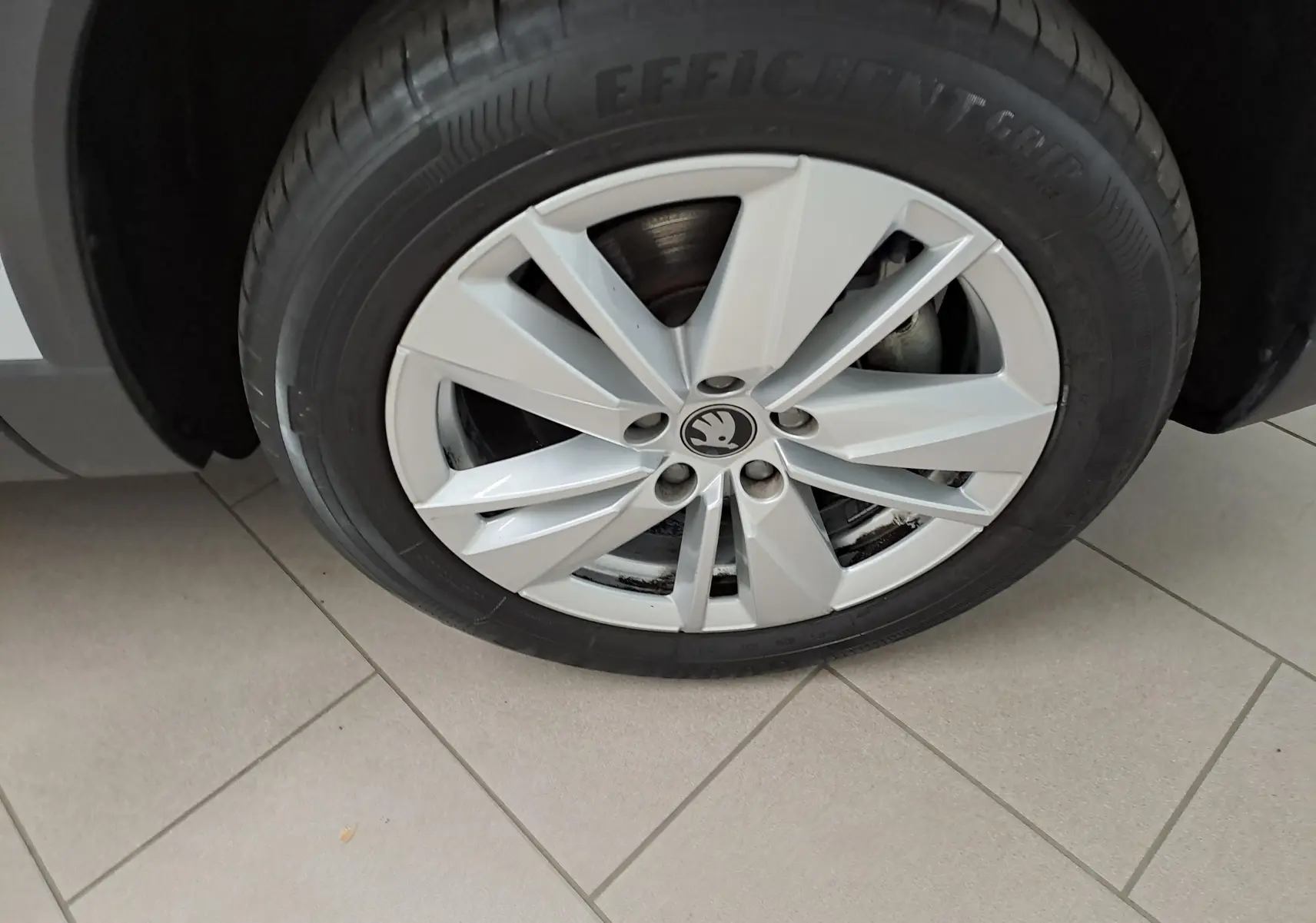 Gros plan sur la jante alliage argentée du Skoda Karoq 1.5 TSI 150 DSG7, roue avant droite sur sol carrelé.