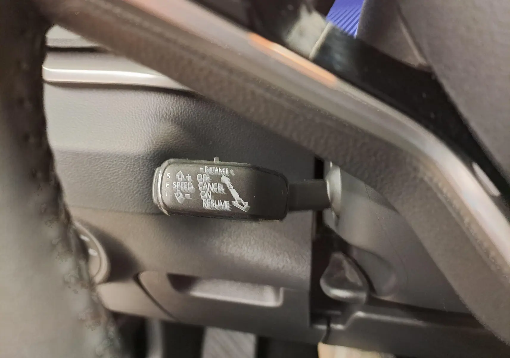 Gros plan sur la commande de régulateur de vitesse au volant d’un Skoda Karoq 2025, intérieur noir.