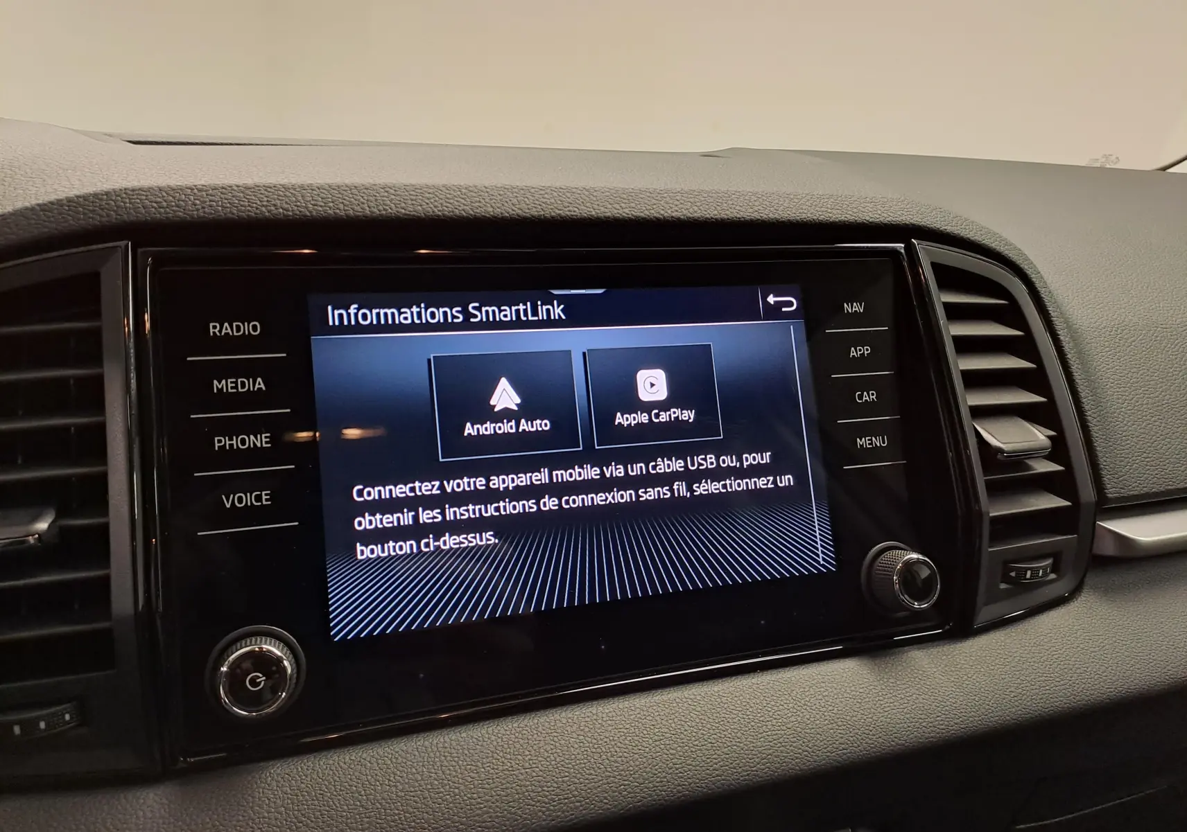 Écran tactile central du Skoda Karoq 2025 affichant les options Android Auto et Apple CarPlay, entouré de commandes noires.