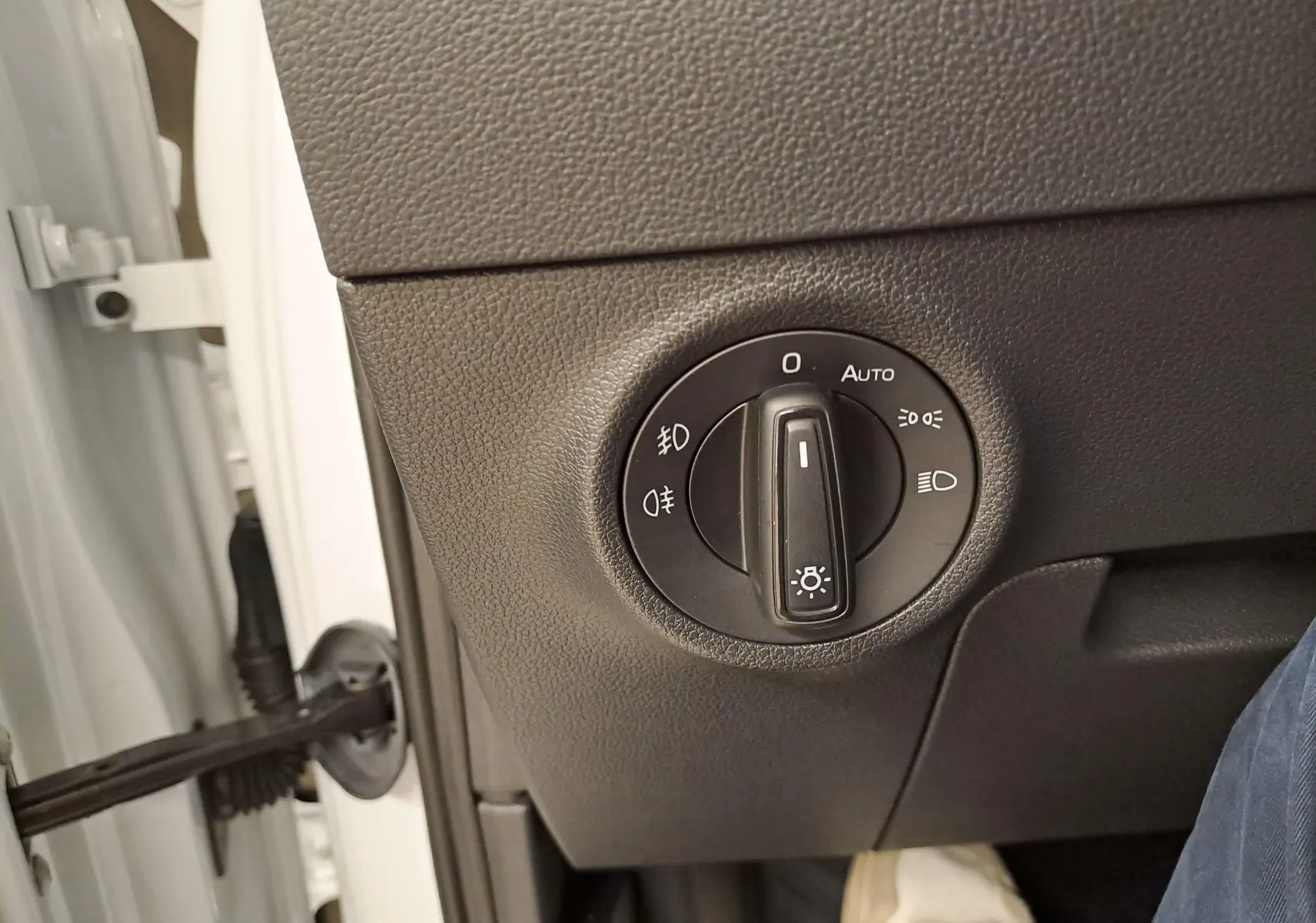 Gros plan sur le bouton de commande des phares à gauche du tableau de bord du Skoda Karoq blanc Lune.