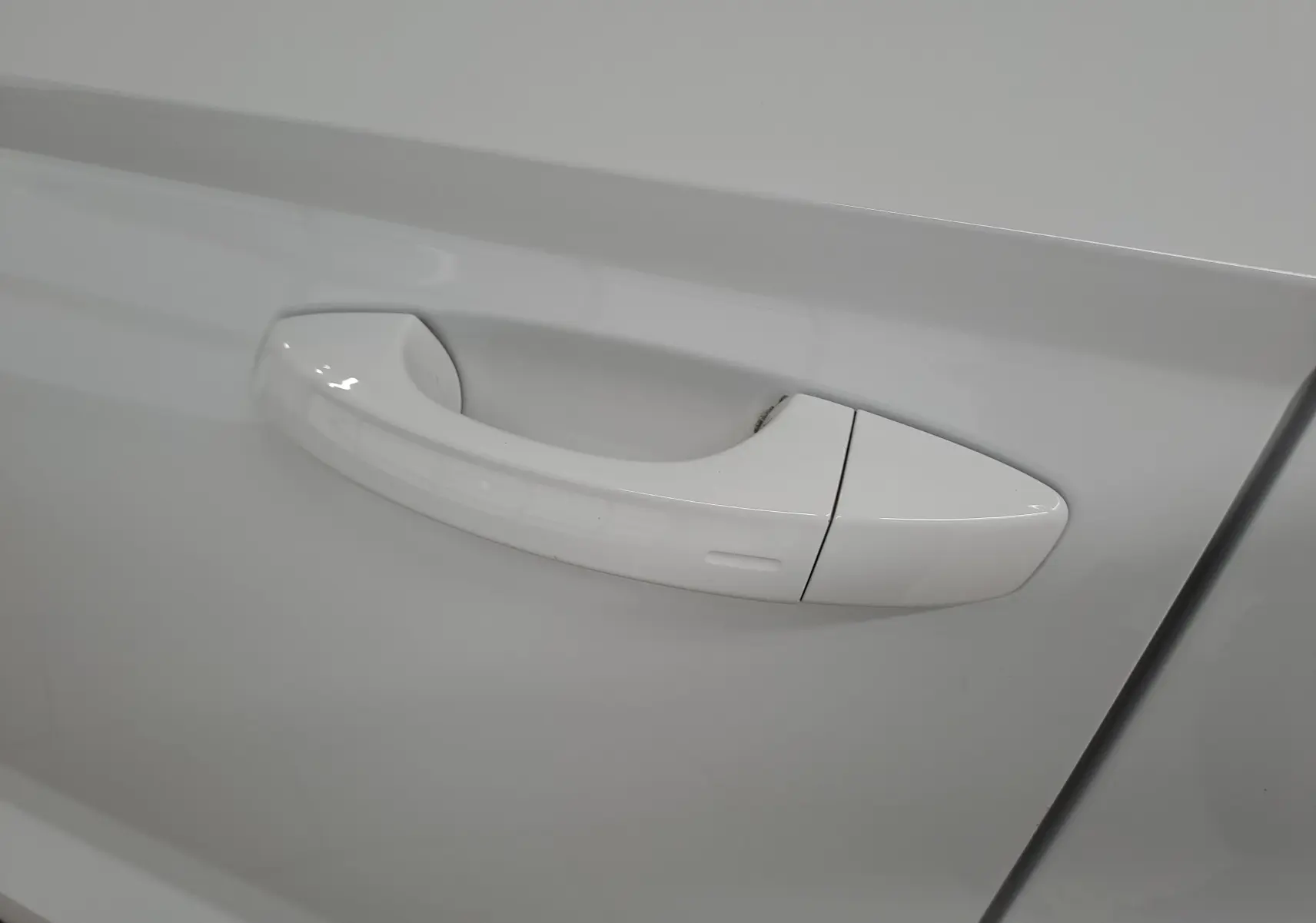 Poignée de porte blanche Lune du côté gauche d'un Skoda Karoq 1.5 TSI 150 DSG7 avec finition chromée autour des vitres.