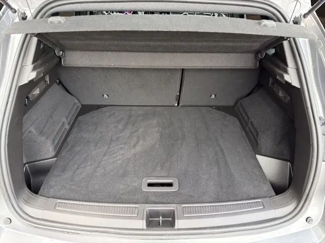 Vue de l'intérieur du coffre ouvert du Renault Austral gris Casiopee, montrant un espace de chargement propre et bien fini.