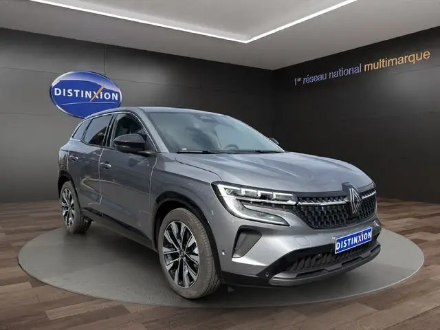 Vue 3/4 avant d’un Renault Austral gris Casiopee avec jantes alliage 19’’ Komah noir dans un showroom.