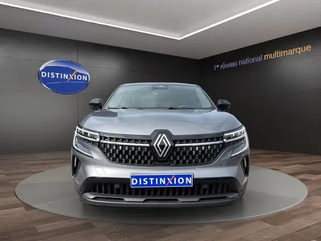 Vue frontale d'un Renault Austral gris Casiopee avec calandre noire et logo Renault proéminent, en showroom Distinxion.
