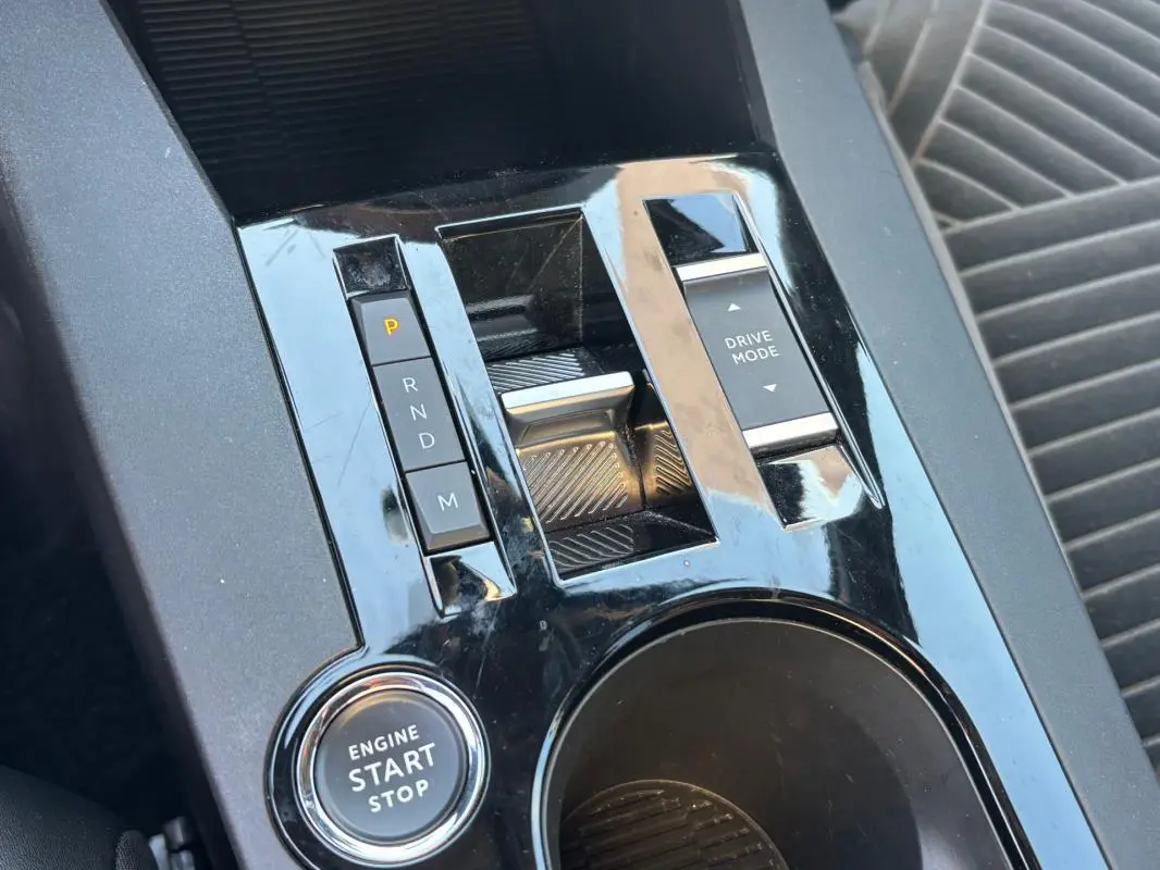 Gros plan sur la console centrale noire brillante de la Lancia Ypsilon 2025 avec bouton start/stop et commandes boîte auto.