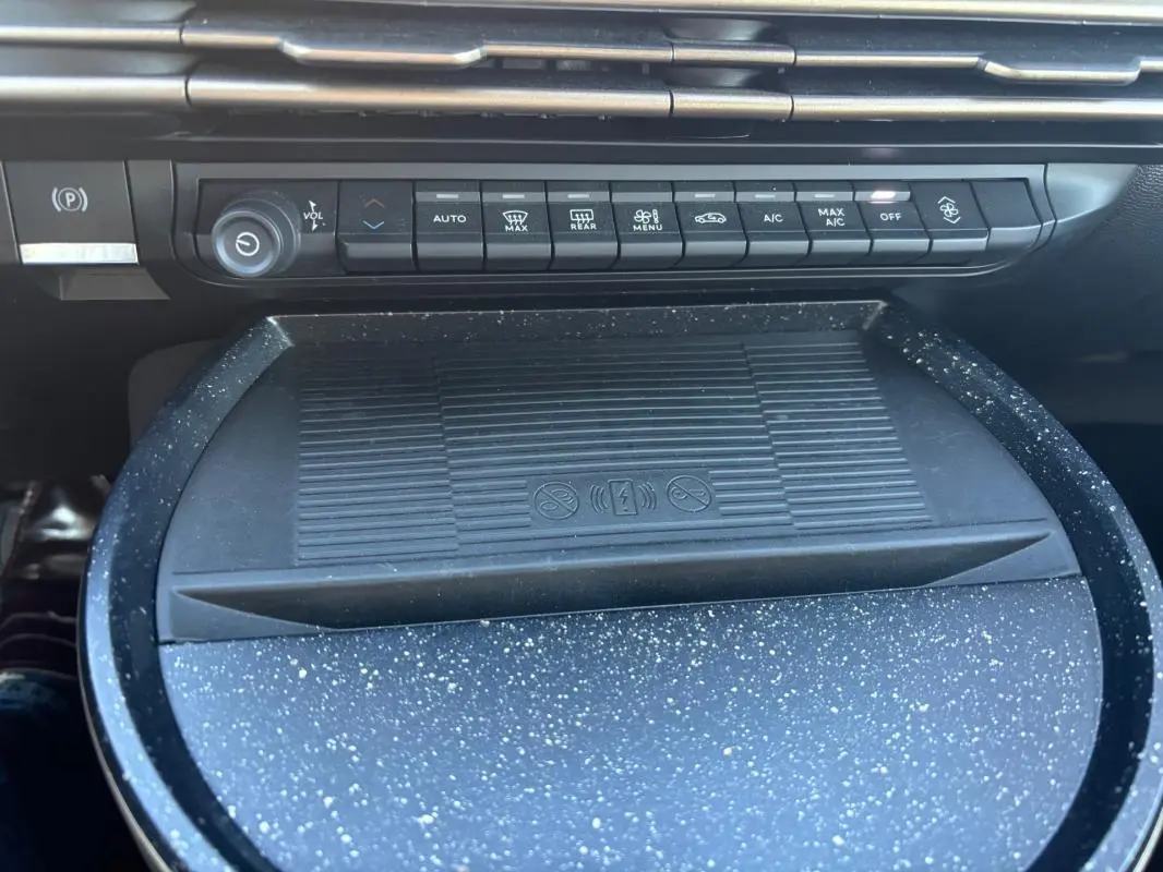 Gros plan sur la console centrale de la Lancia Ypsilon 2025, montrant les commandes climatisation et un espace de rangement texturé gris.