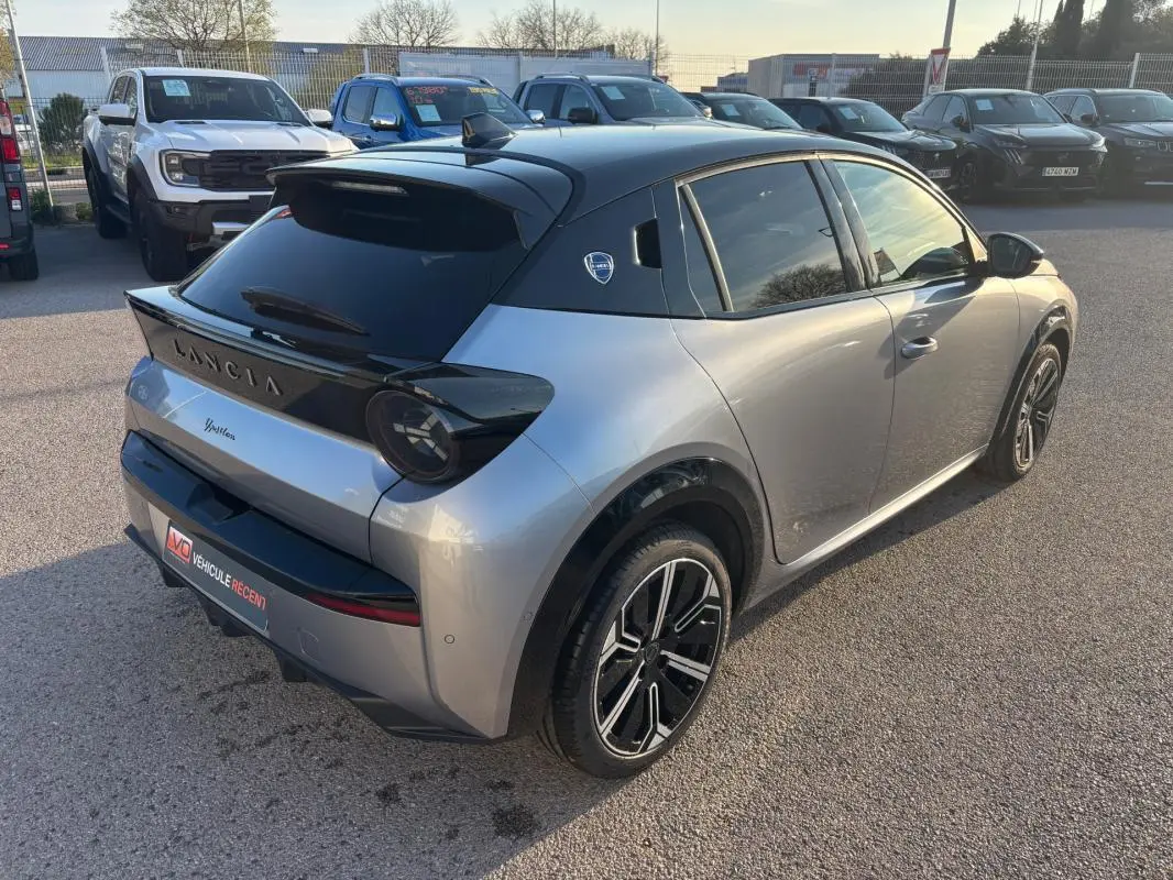 Vue 3/4 arrière droite d'une Lancia Ypsilon gris métallisé avec toit noir et jantes 17 pouces au soleil.