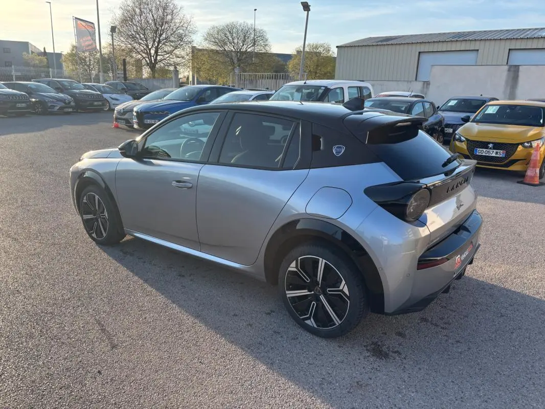 Vue 3/4 arrière droite d'une Lancia Ypsilon gris métallisé avec toit noir et jantes 17 pouces, stationnée en extérieur.