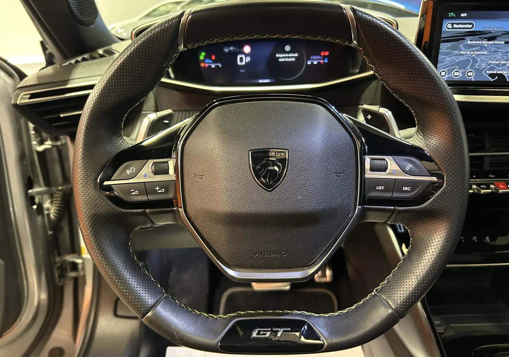 Vue rapprochée du volant cuir perforé GT du Peugeot 2008 2024 avec commandes intégrées et tableau de bord numérique.