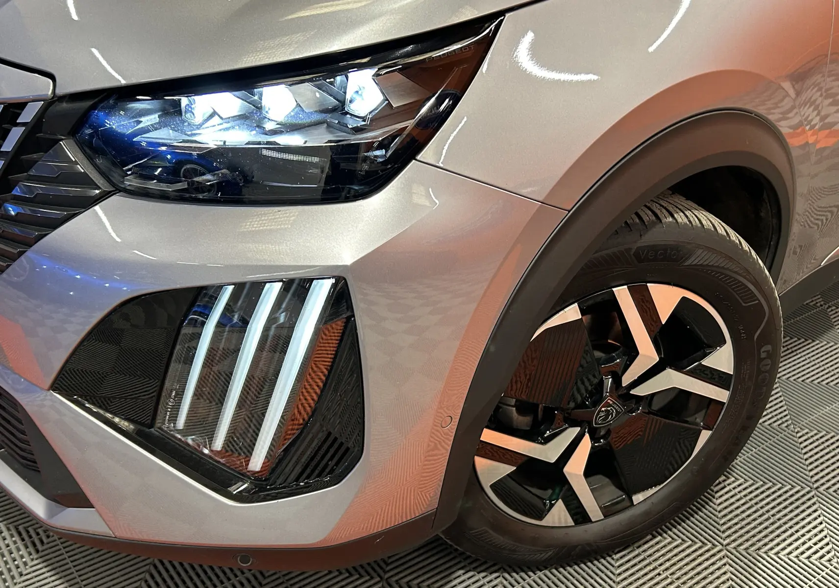 Gros plan sur l’avant droit gris Artense du Peugeot 2008 2024, mettant en valeur les phares LED et la jante noire et argent.