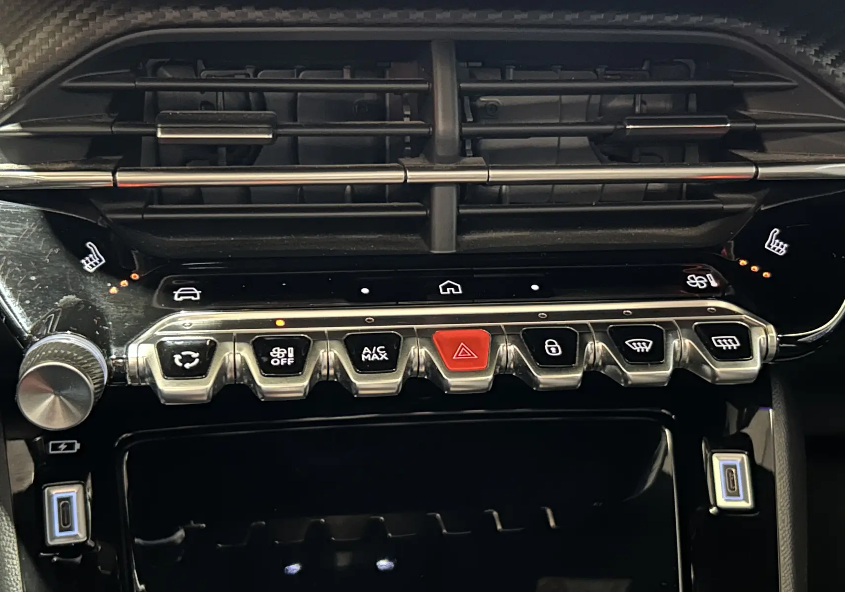 Gros plan sur la console centrale du Peugeot 2008 2024, boutons de climatisation et sièges chauffants activés.