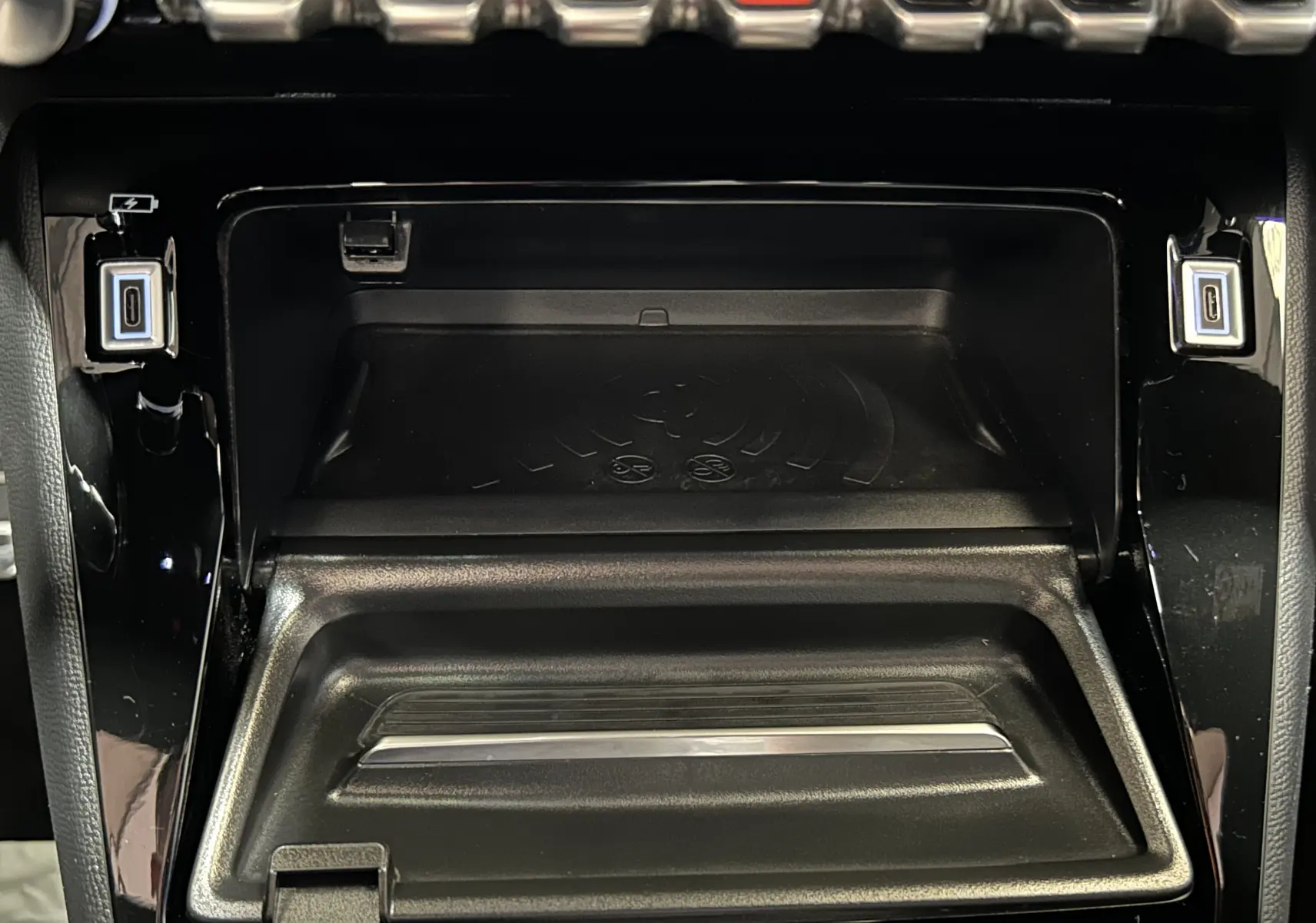 Gros plan sur la console centrale noire du Peugeot 2008 2024, montrant le compartiment de charge sans fil et deux ports USB-C.