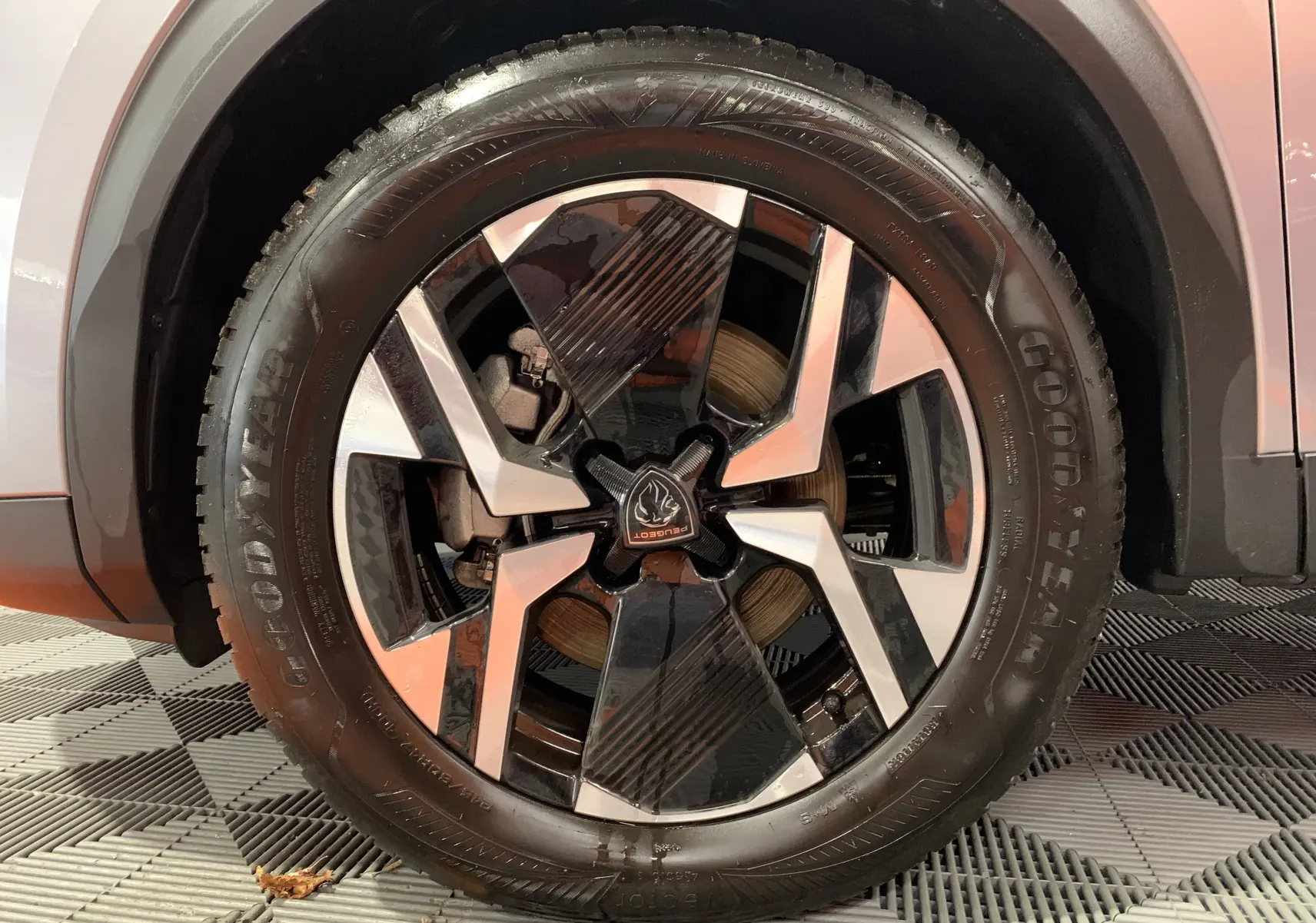 Gros plan sur la jante avant droite du Peugeot 2008 gris Artense avec logo Peugeot au centre et pneu Goodyear.