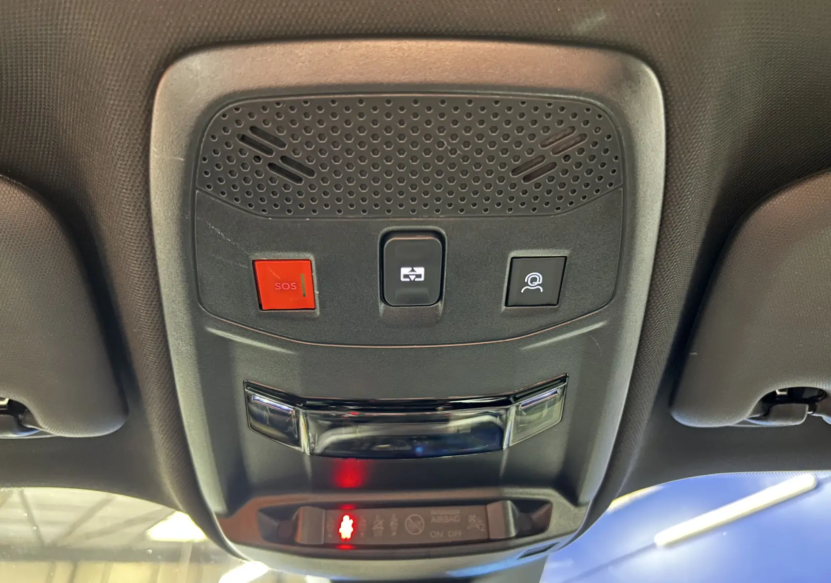 Vue en contre-plongée du panneau de commande au plafond intérieur du Peugeot 2008 gris Artense, avec bouton SOS rouge et éclairage intégré.