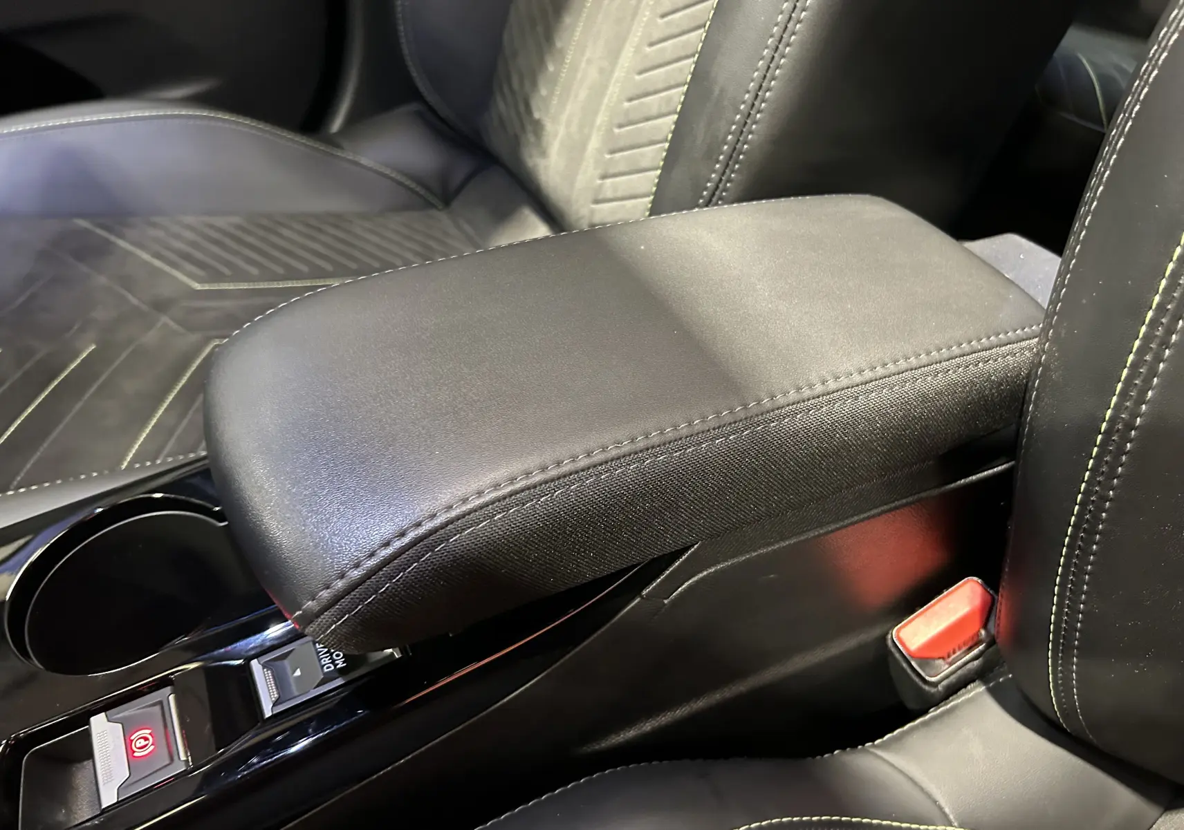 Gros plan sur l'accoudoir central en cuir noir et les sièges partiellement visibles de la Peugeot 2008 GT PACK 2024.