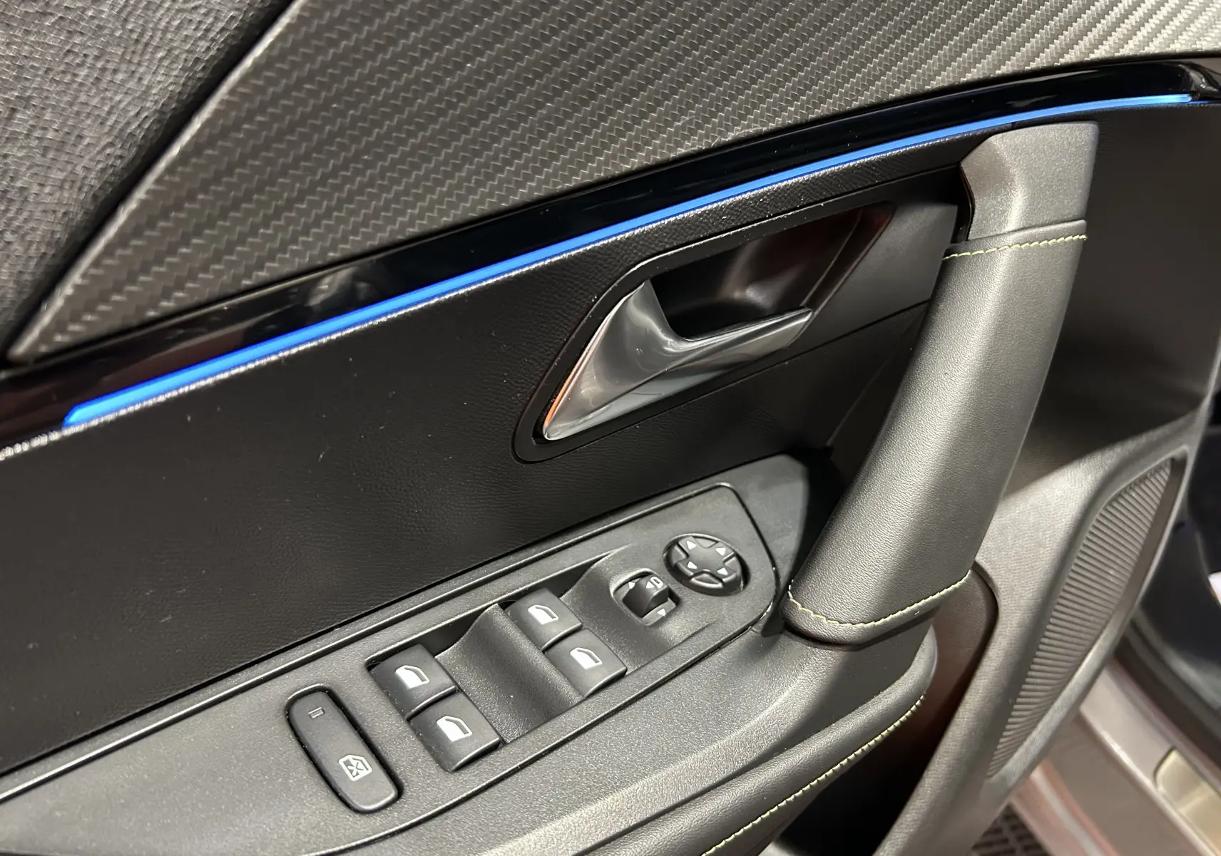 Gros plan sur la porte côté conducteur du Peugeot 2008 gris Artense, avec commandes électriques et surpiqûres jaunes.