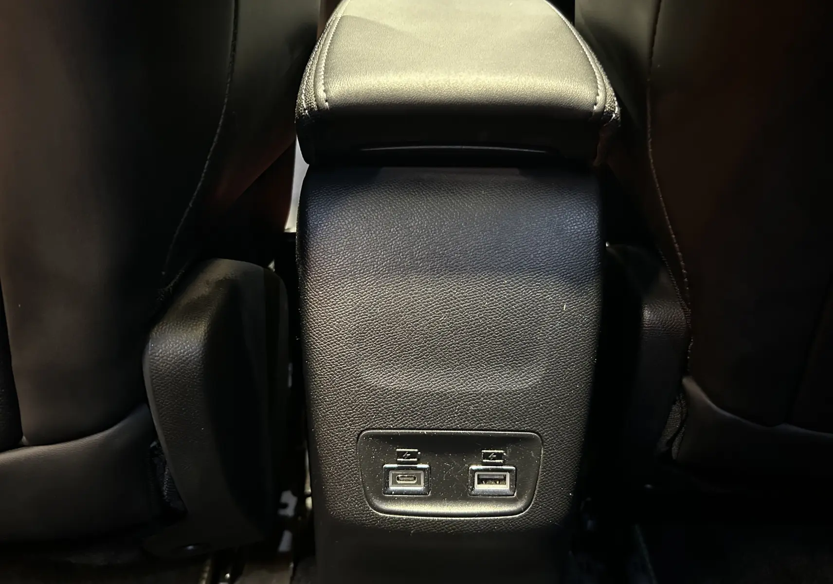 Gros plan sur la console centrale arrière noire du Peugeot 2008 2024 avec deux ports USB visibles entre les sièges.