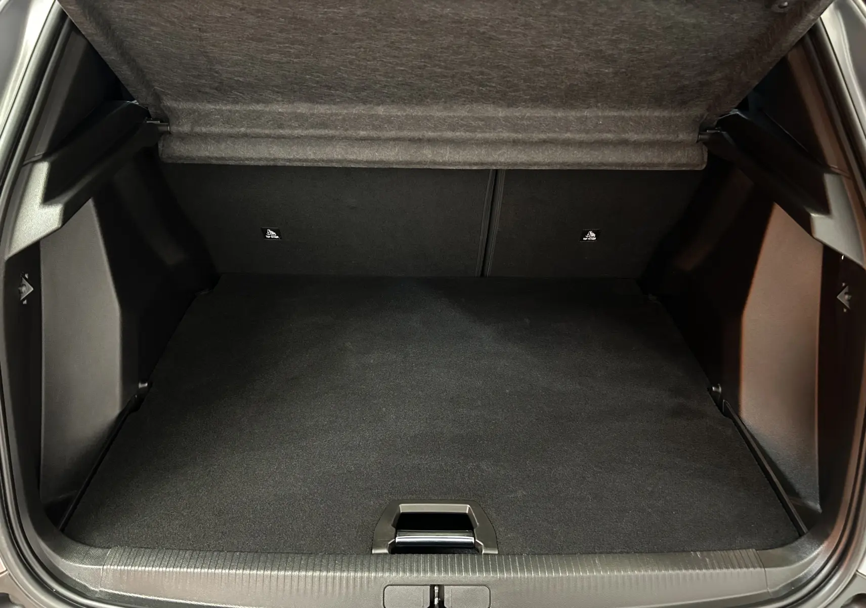 Coffre ouvert vu de l'arrière du Peugeot 2008 gris Artense, montrant un espace de chargement propre et spacieux.