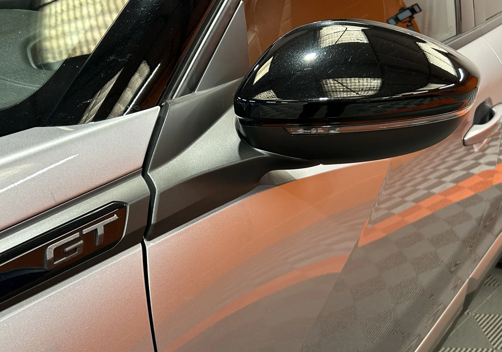 Gros plan sur le rétroviseur noir et l’emblème GT du côté gauche d’un Peugeot 2008 gris Artense.