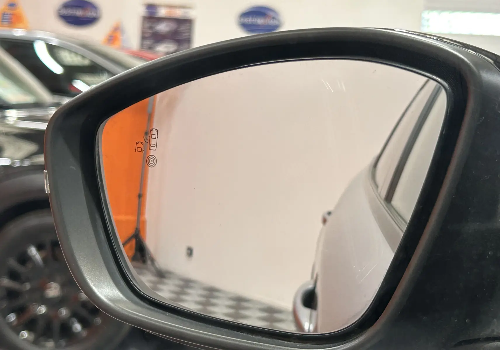 Rétroviseur extérieur gauche montrant la carrosserie gris Artense du Peugeot 2008 GT PACK 2024 en intérieur showroom.