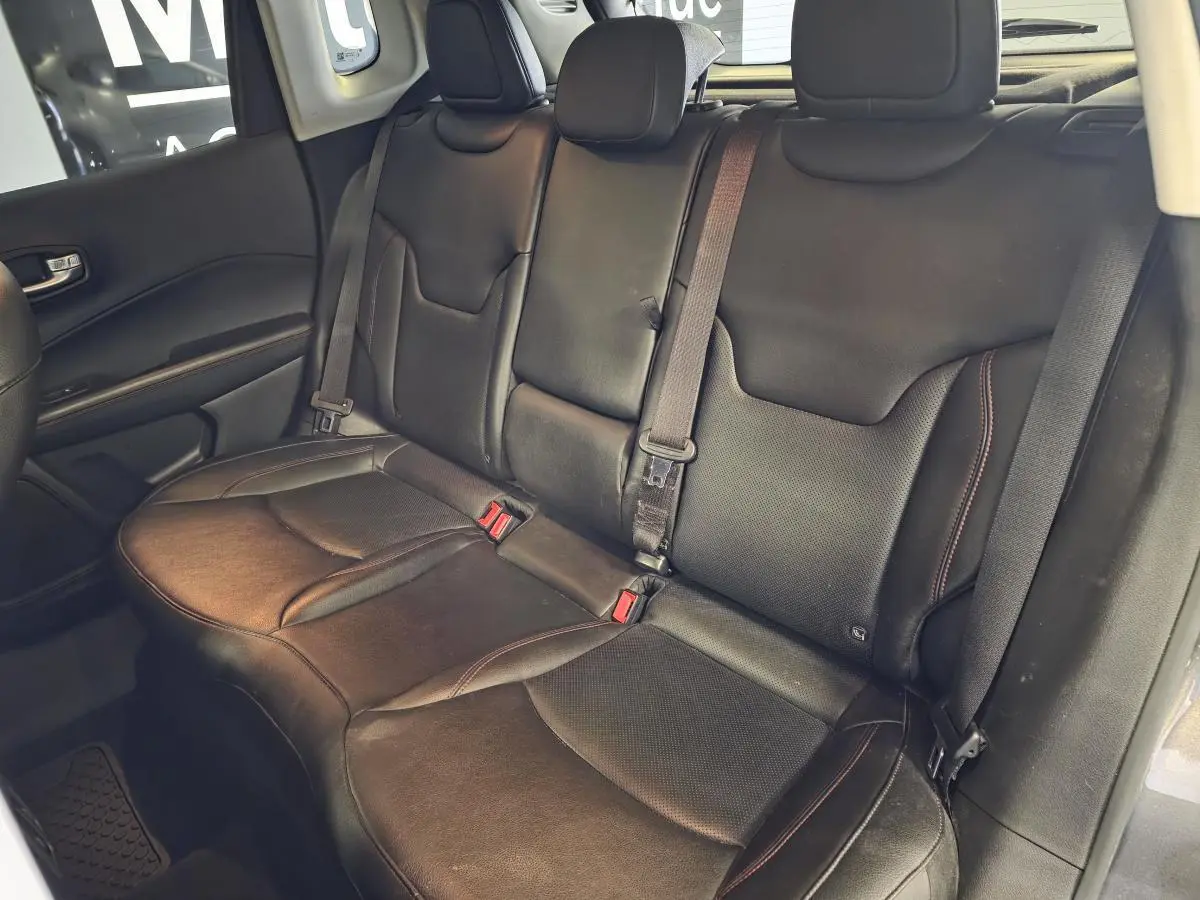 Vue intérieure montrant la banquette arrière en cuir noir du Jeep Compass Trailhawk, avec ceintures de sécurité visibles.