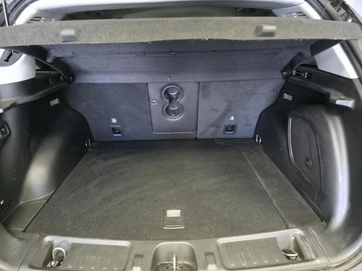 Coffre ouvert vu de l'arrière d'un Jeep Compass gris, montrant l'espace de chargement et la moquette noire.