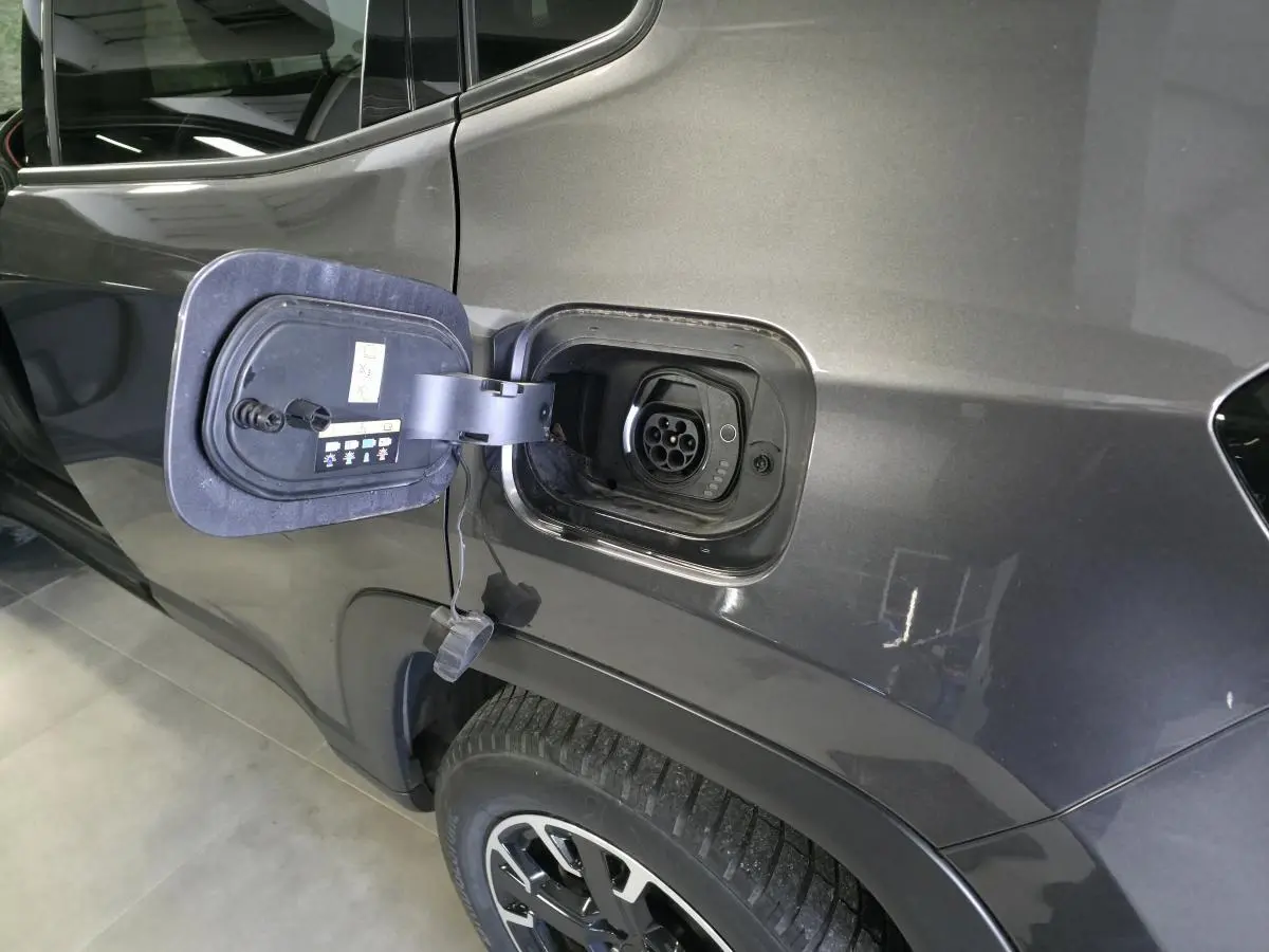 Prise de recharge ouverte côté gauche arrière d’un Jeep Compass gris métallisé avec jante noire et argent.