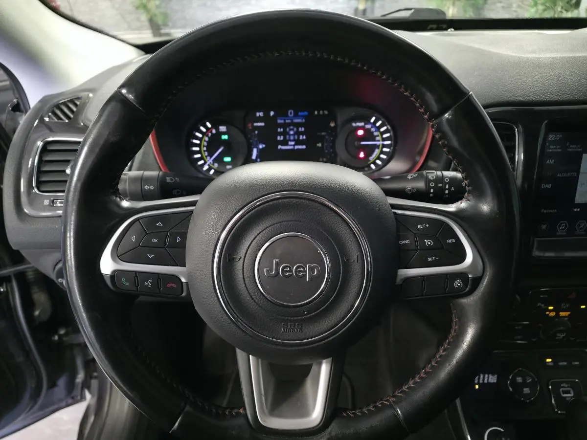 Vue rapprochée du volant noir en cuir avec commandes multifonctions du Jeep Compass Trailhawk hybride rechargeable.