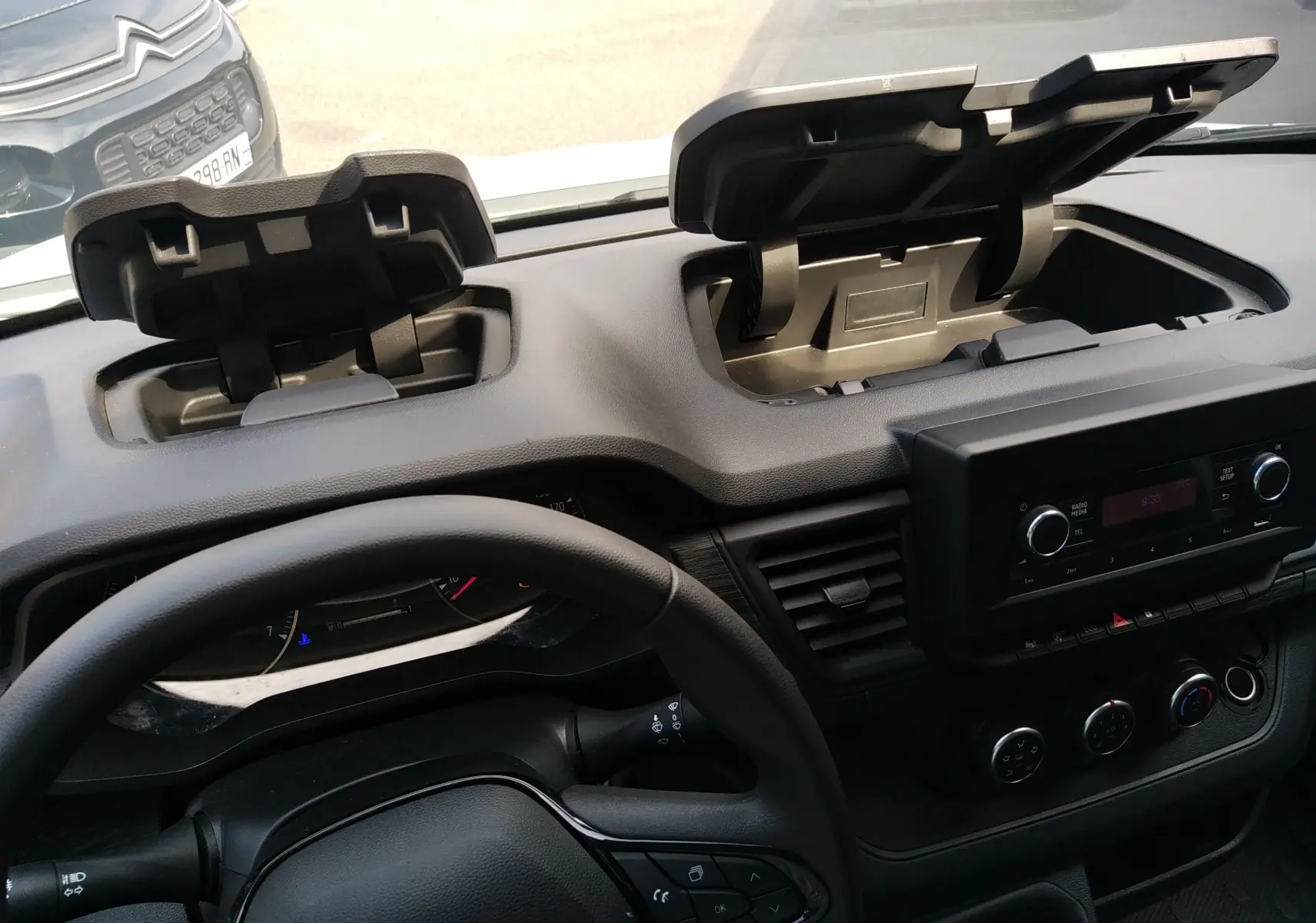 Vue intérieure du tableau de bord du Renault Trafic Fourgon blanc 2024, avec deux compartiments de rangement ouverts.