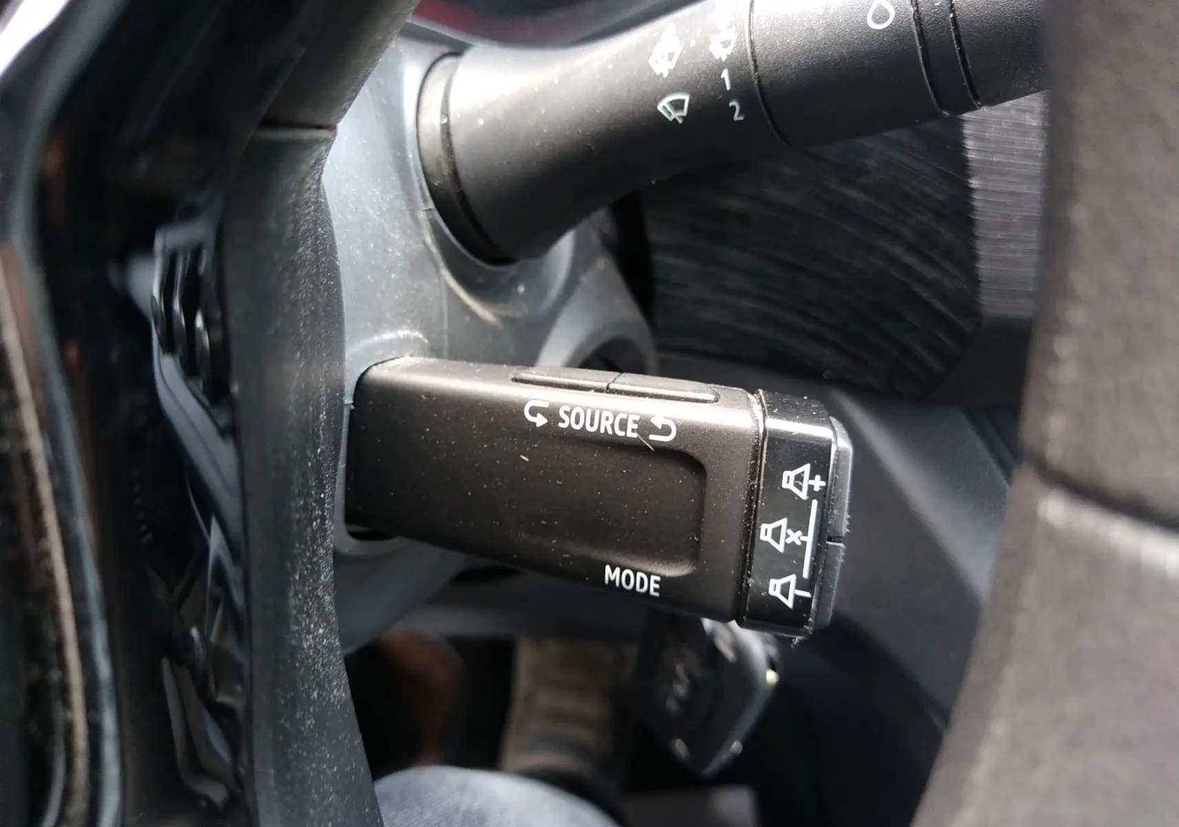 Gros plan sur la commande au volant du Renault Trafic Fourgon blanc 2024, avec boutons source et mode visibles.