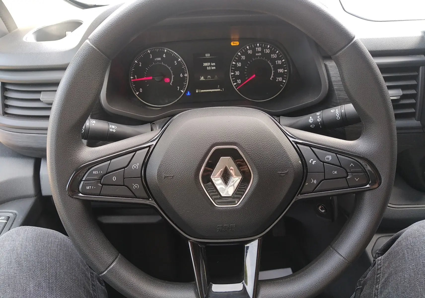 Vue rapprochée du volant noir du Renault Trafic Fourgon 2024 avec commandes intégrées et tableau de bord visible.