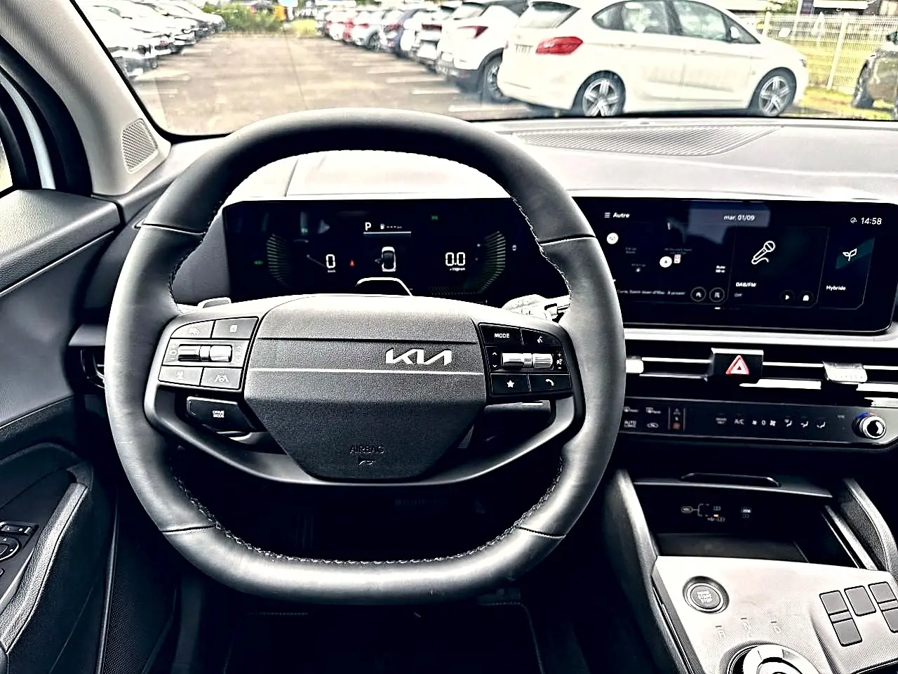 Vue intérieure centrée sur le volant noir multifonction du Kia Sportage 1.6 hybride 2026 avec tableau de bord digital et écran tactile.
