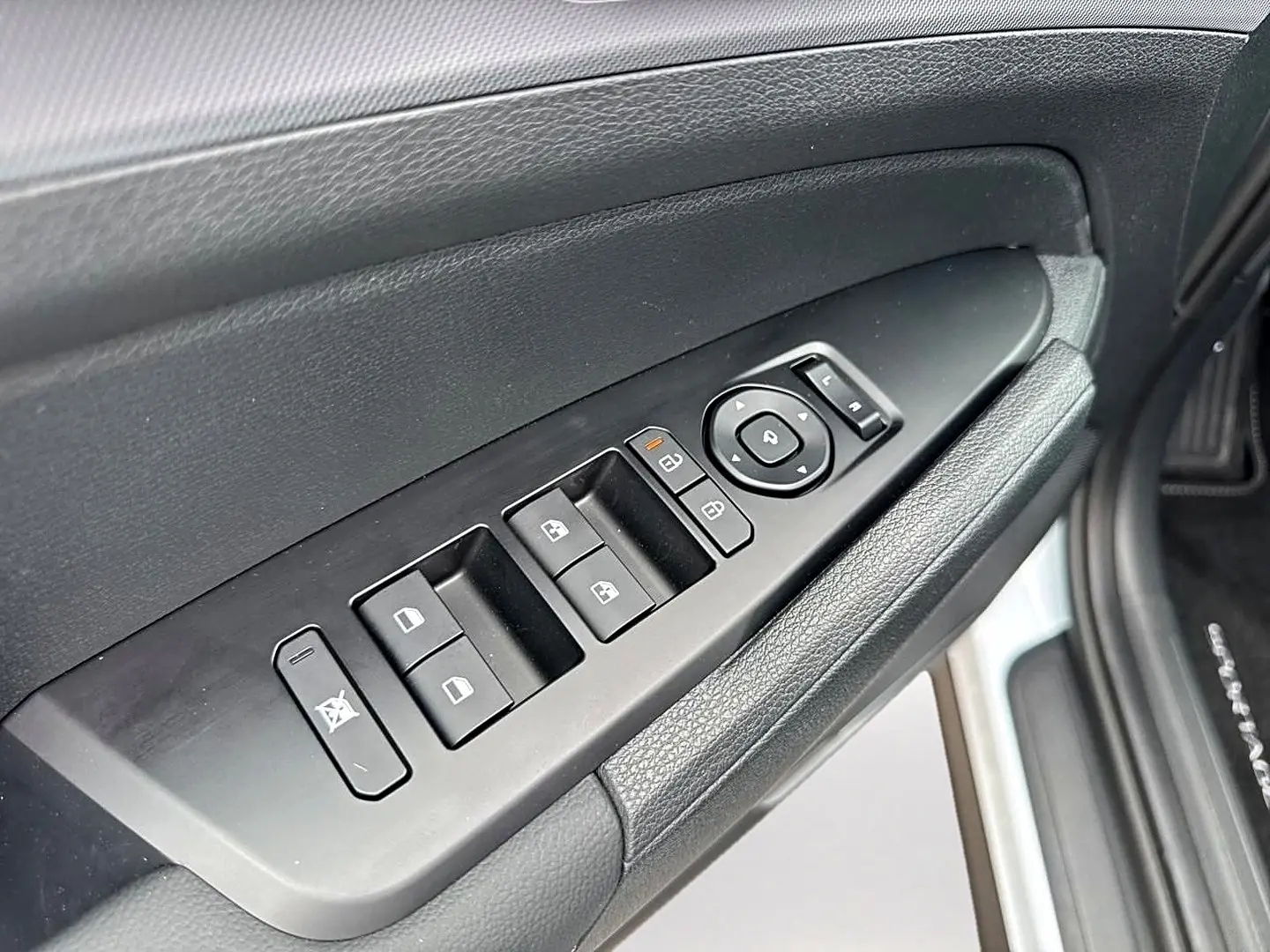 Vue rapprochée du panneau de commandes des vitres côté gauche intérieur d’un KIA Sportage blanc avec boutons noirs.