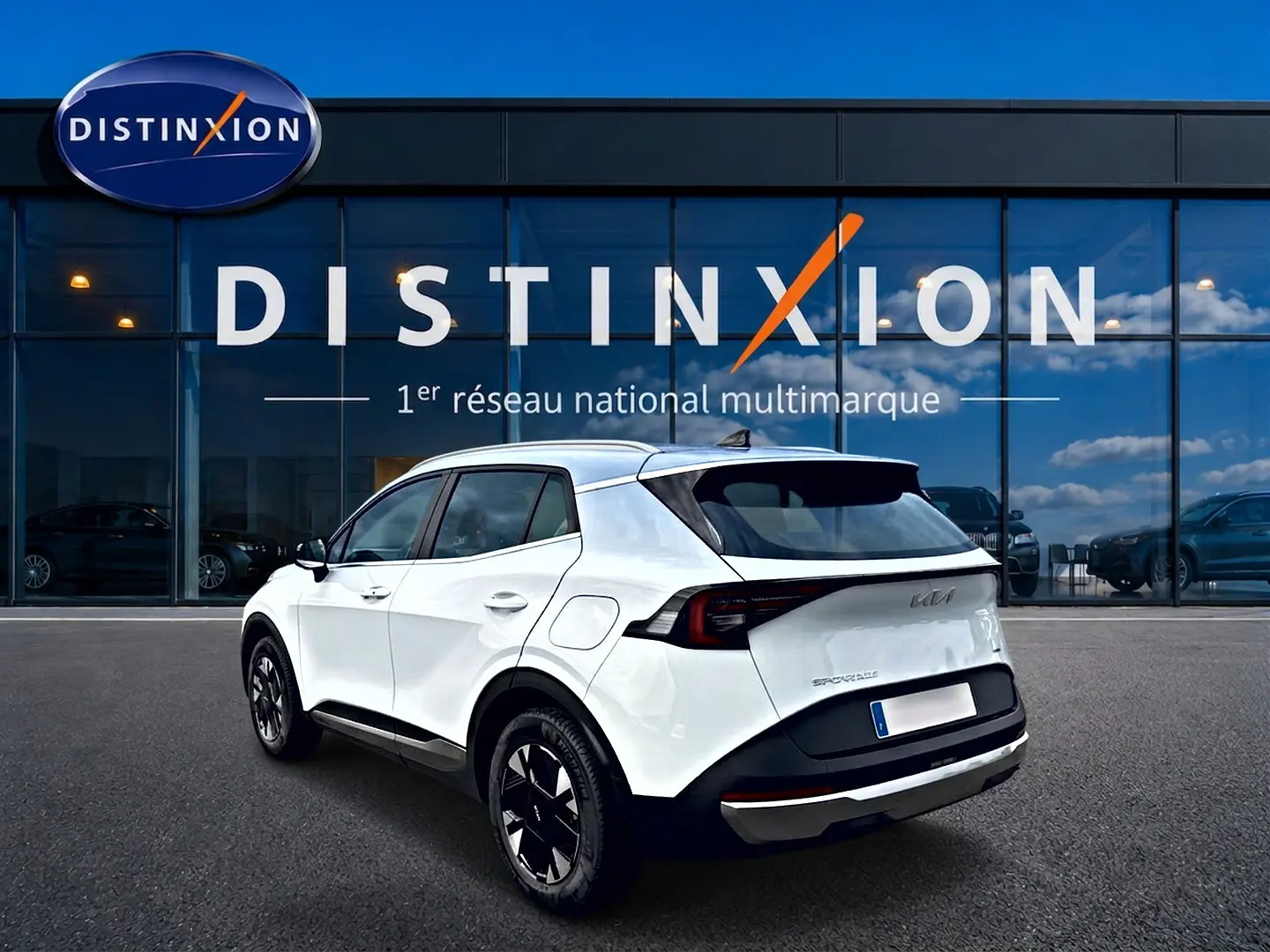 Vue 3/4 arrière droite d'un KIA Sportage blanc 2026 avec jantes alu noires et feux arrière LED distinctifs.
