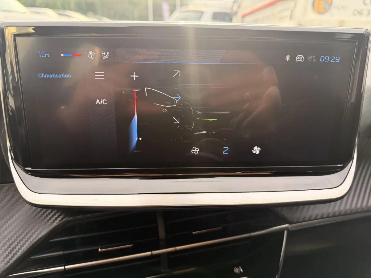 Écran tactile central de la Peugeot 208 blanc, affichant les réglages de climatisation dans l'habitacle.
